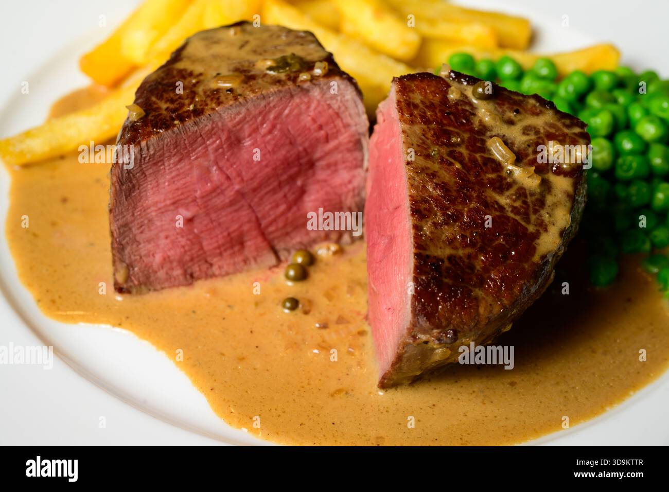 Bistecca di manzo con filetto Mignon con salsa peperoncino verde con patatine fritte e piselli chiamata Steak au Poivre Vert in francese Foto Stock
