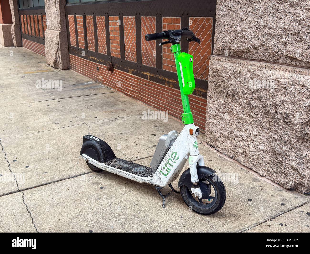 Denver, Colorado, USA - 4 giugno 2025: Scooter elettrico del sistema di condivisione Lime lasciato incustodito su un marciapiede nel centro di Denver. - Immagine stock catturata con smartphone