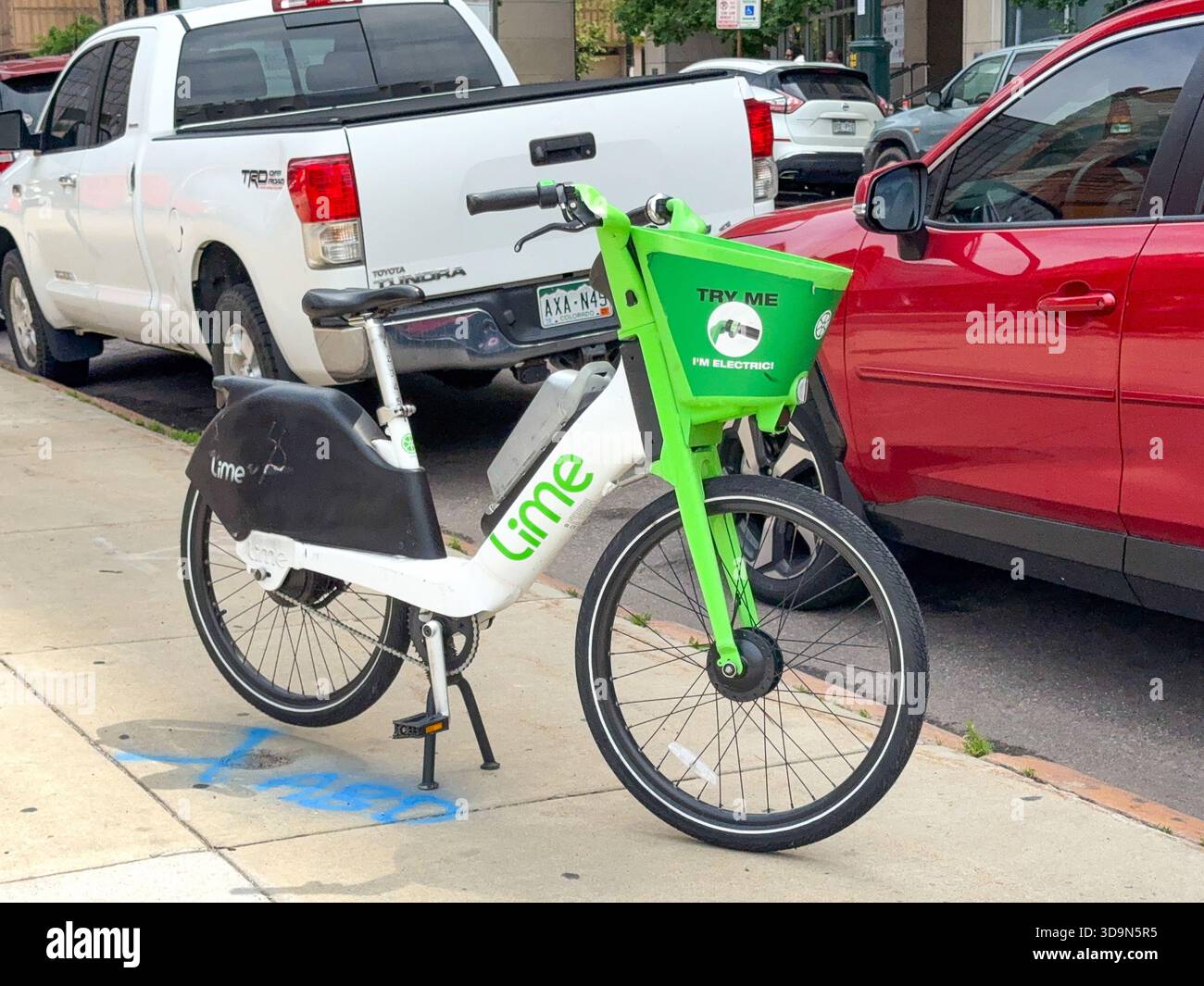 Denver, Colorado, USA - 4 giugno 2025: Bici elettrica del sistema di condivisione biciclette Lime Bike lasciata incustodita su un marciapiede nel centro di Denver. - Immagine stock catturata con smartphone