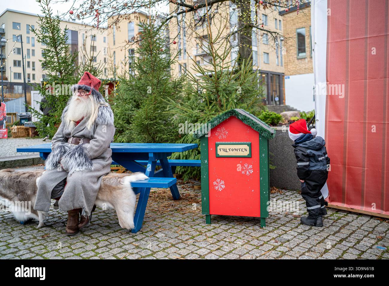 Ragazzo in cerca di regali dietro la scatola delle lettere al mercatino di Natale nello storico paesaggio industriale di Norrköping, Svezia Foto Stock