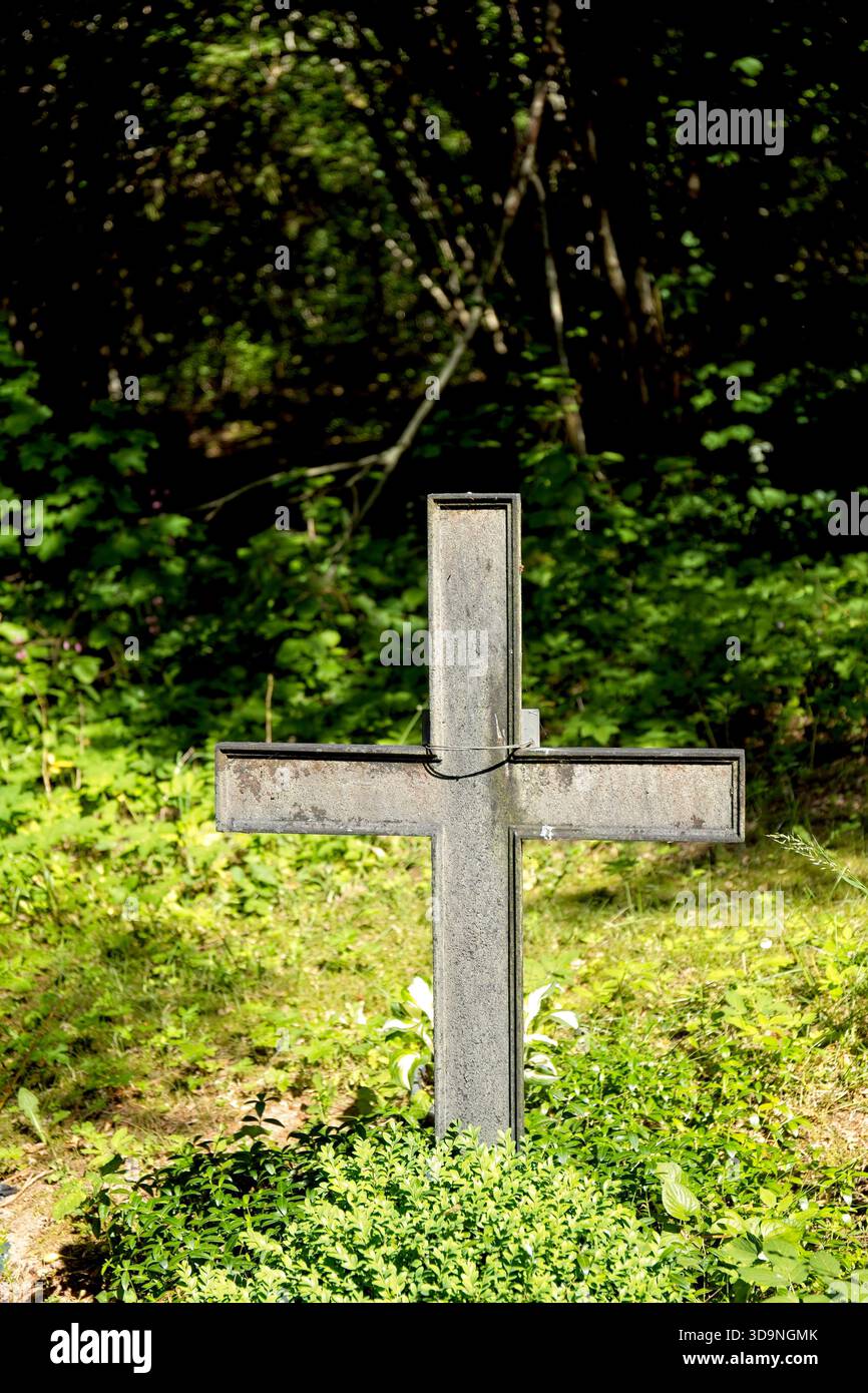 Ornata croce in metallo antico, in un cimitero circondato da vegetazione lussureggiante, cimitero abruzzese, Saaremaa, Estonia. Foto Stock