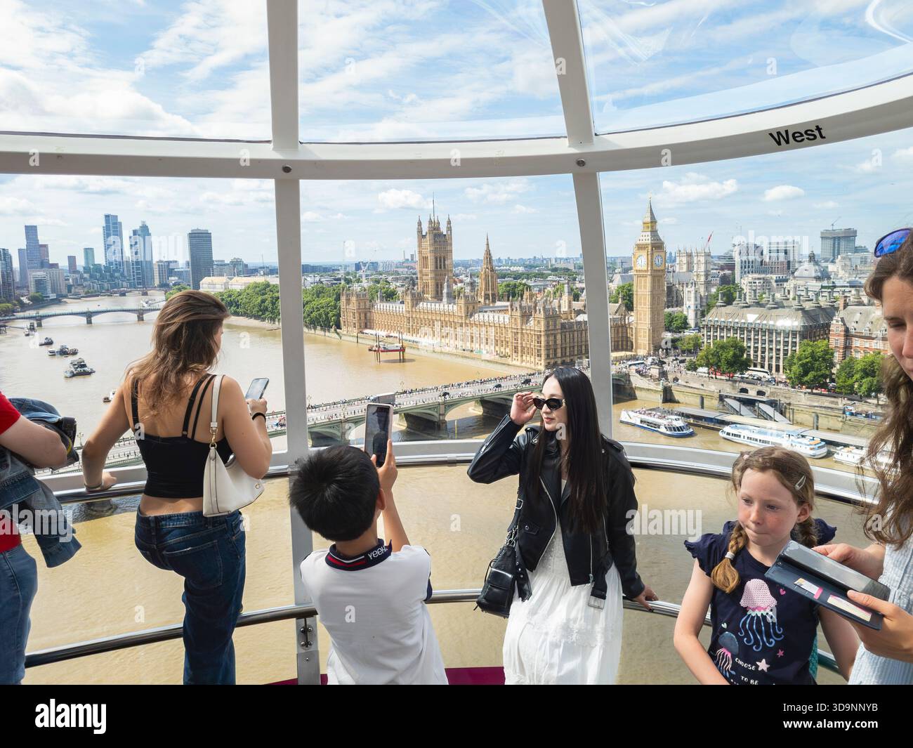 Turisti e visitatori che guardano fuori dalla capsula passeggeri del London Eye attraverso il Big Ben e le Houses of Parliament, Londra, Regno Unito Foto Stock