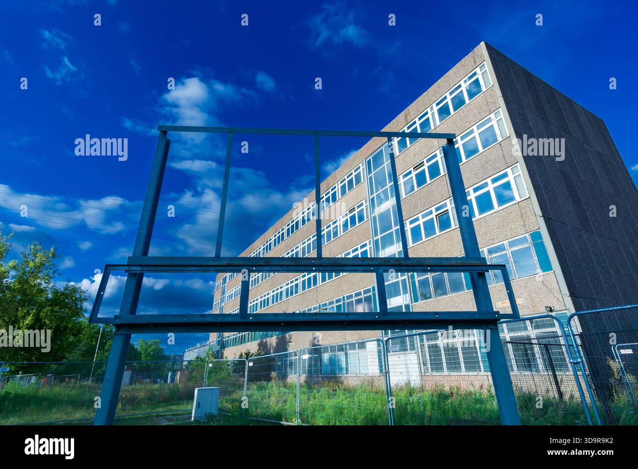Telaio per cartelloni vuoto di fronte a un edificio di uffici in cemento in stile industriale, fotografato da un'angolazione bassa. Foto Stock