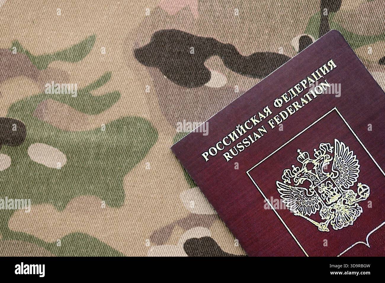 Passaporto russo su tessuto mimetico multicam primo piano. Concetto di esercito russo e invasione in Ucraina Foto Stock