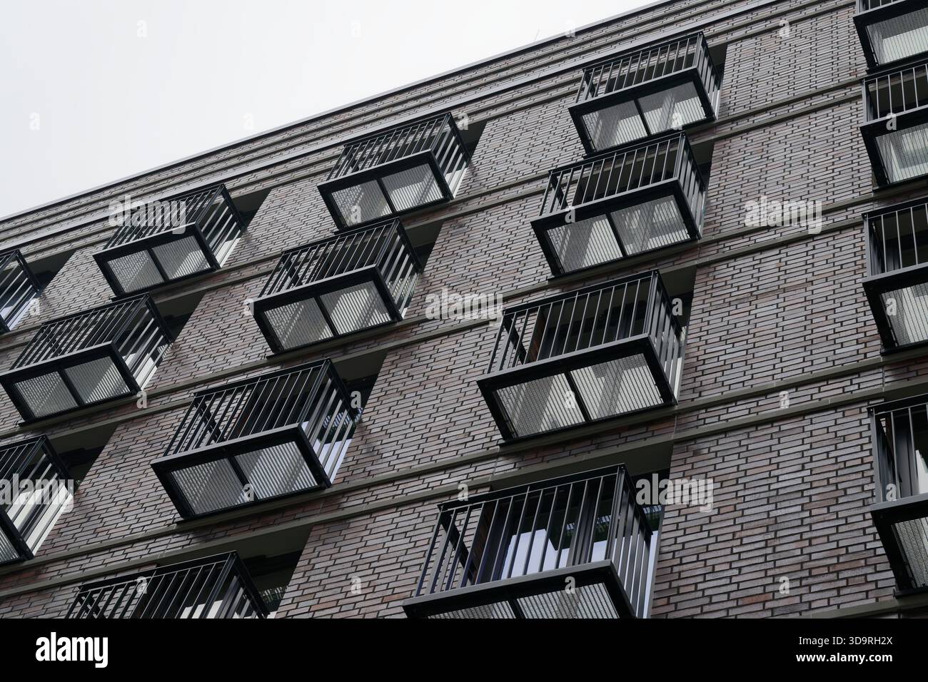 Edificio residenziale a piu' piani in mattoni bianchi caratterizzato da numerosi balconi rettangolari identici con ringhiere in metallo che creano una scatola uniforme l Foto Stock