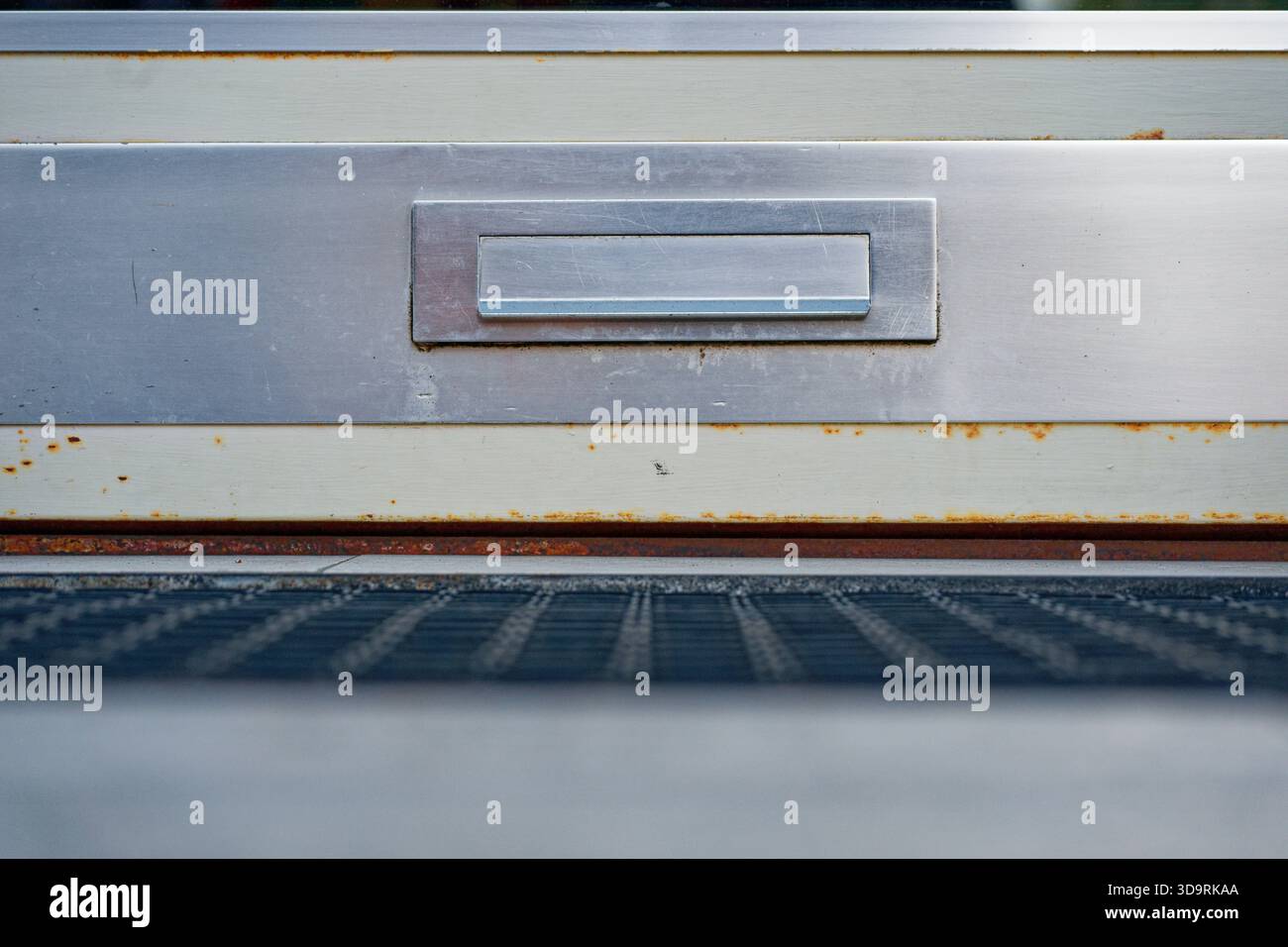 Una piastra di metallo è dotata di uno slot di caricamento incorporato con un lembo incernierato per l'inserimento di lettere probabilmente installate su una porta o su una parete vicino all'ingresso di un residen Foto Stock