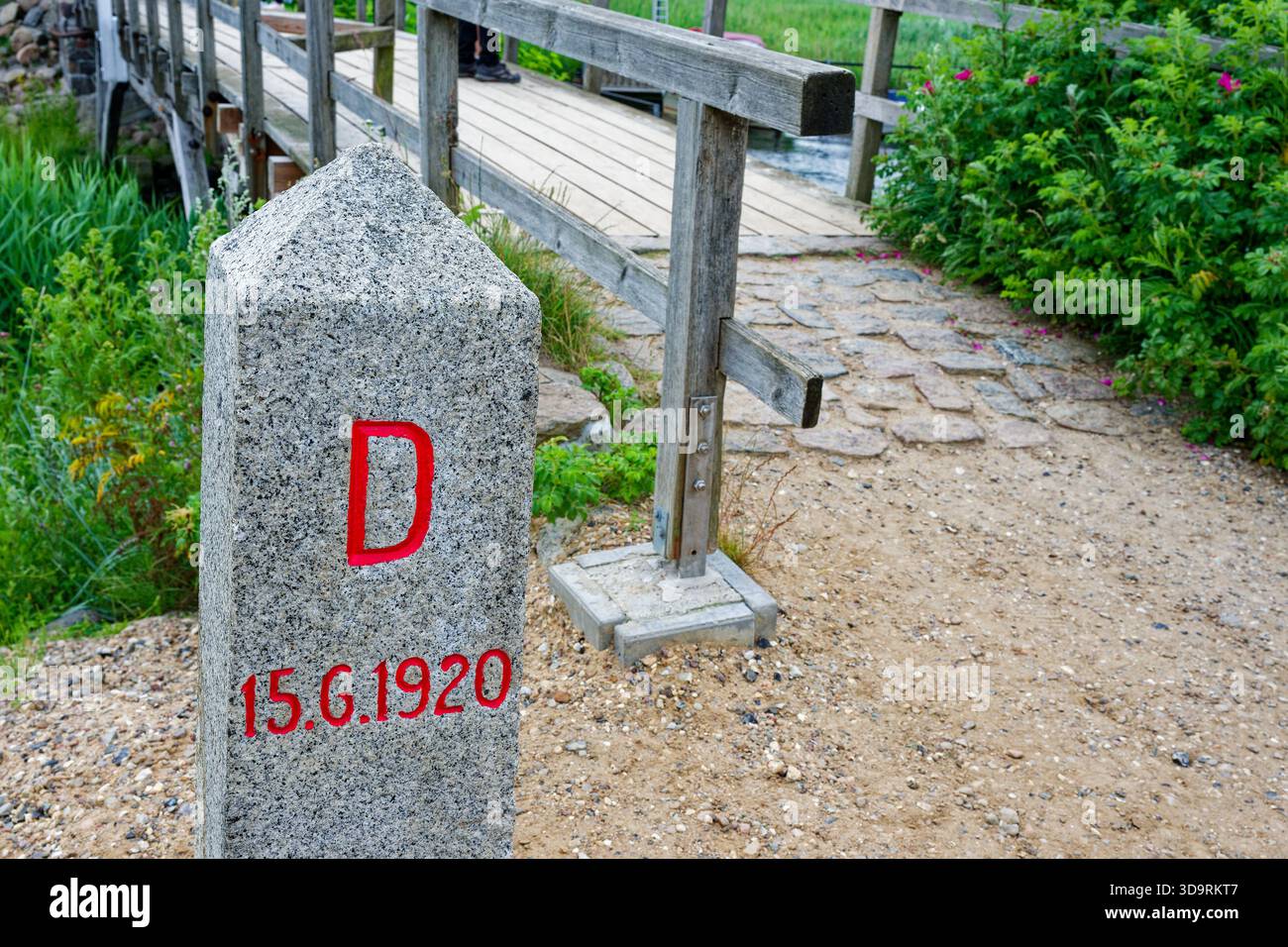 Un piccolo ponte in legno, accanto ad esso si trova un palo in pietra dipinto con una lettera rossa D e l'iscrizione DR P e data 15.6,1920, a Wassersleben vicino Den Foto Stock