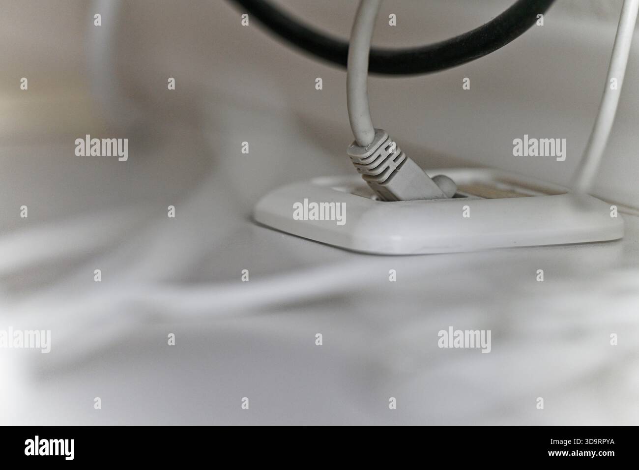 Un coperchio rotondo in plastica è posizionato a filo su un piano portapaziente bianco, i cavi cadono ordinatamente attraverso l'apertura e scompaiono sotto, mantenendo l'area di lavoro pulita, ordinata, A. Foto Stock