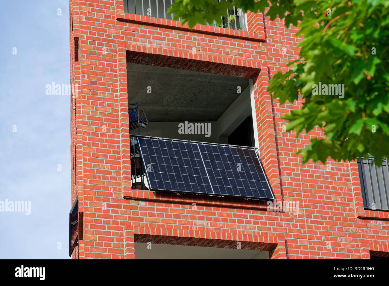 Moderna centrale elettrica con balcone con pannello solare su un edificio di appartamenti in mattoni. Simbolo dell'energia rinnovabile, dell'autosufficienza e dell'ottimizzazione dell'energia domestica Foto Stock