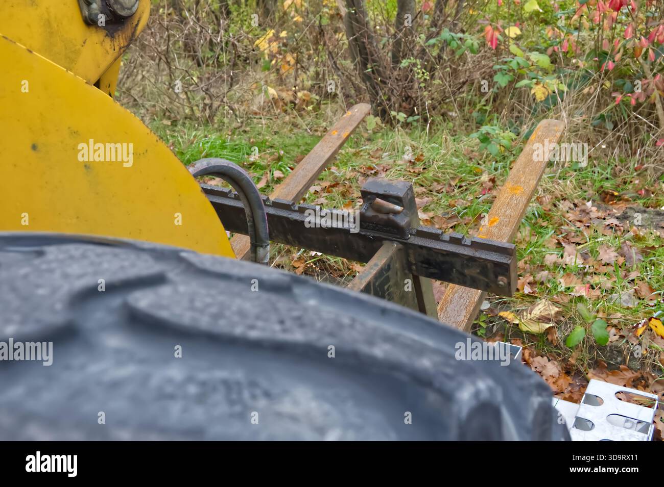 Vista ravvicinata di un componente di macchinari giallo carrello elevatore in cantiere con pneumatico in primo piano, situato in un ambiente naturale all'aperto con wi-fi Foto Stock