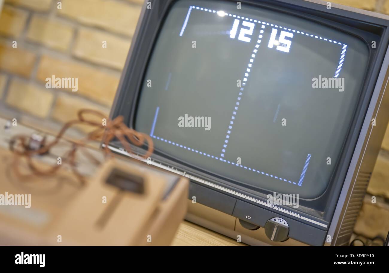 Una televisione d'epoca che mostra un classico videogioco, simile a Pong, con un semplice tabellone che mostra l'ora 12:15. Il televisore è posizionato su una S di legno Foto Stock