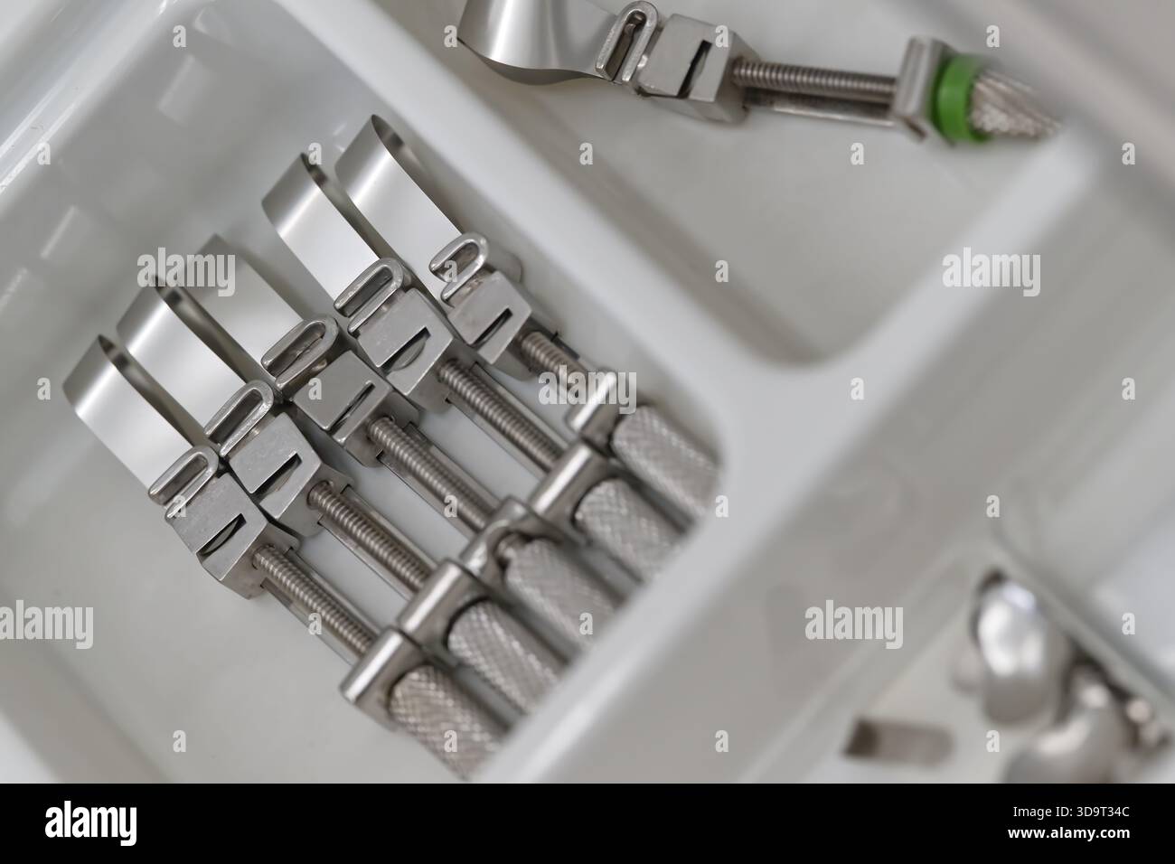Vista ravvicinata di diversi utensili metallici disposti in modo ordinato in un vassoio bianco Gli utensili hanno un design elegante con una finitura lucida, che ne mostra l'esattezza Foto Stock