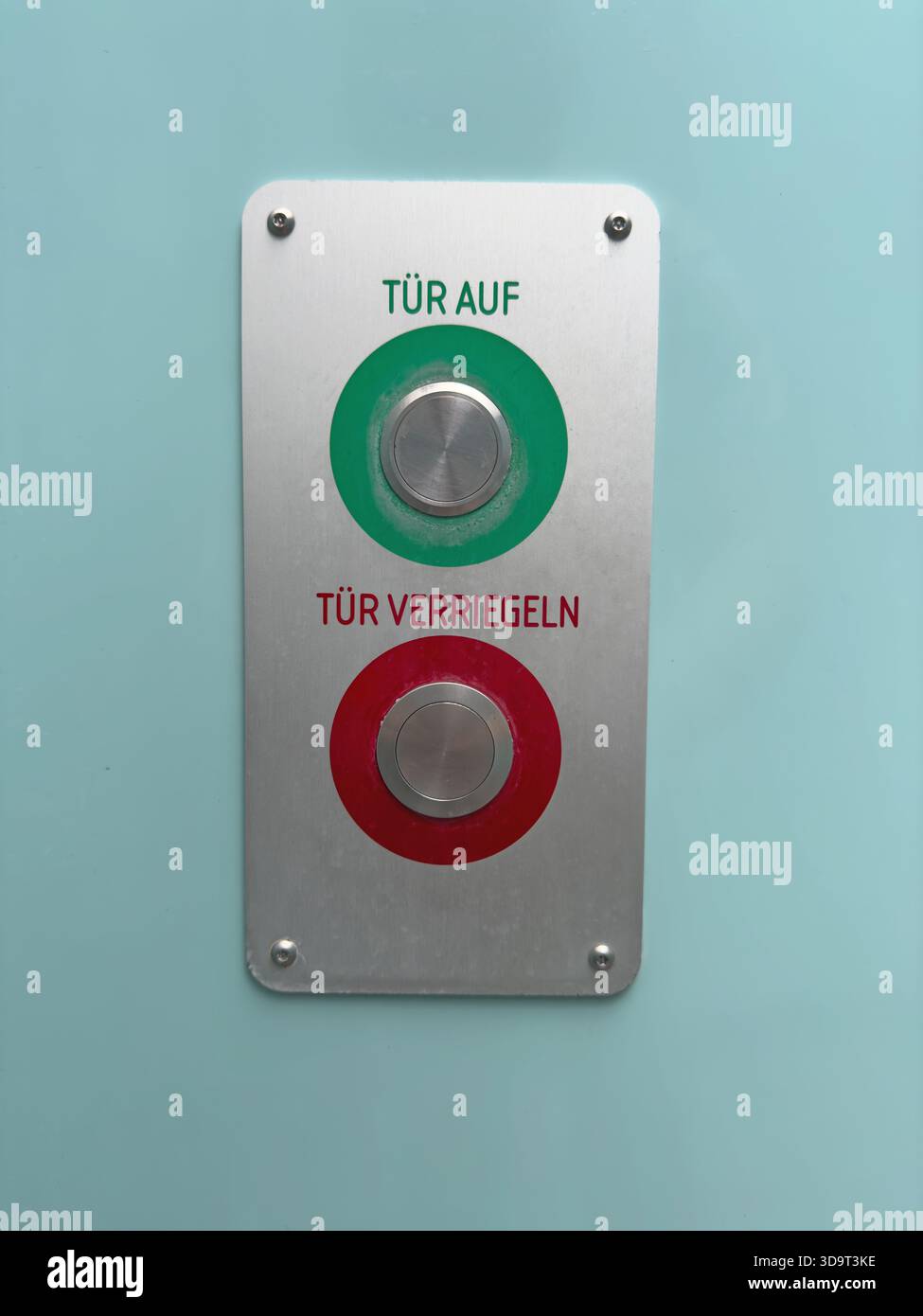 Un pannello di controllo metallico con due pulsanti. Il pulsante superiore è verde e contrassegnato con "Tür AUF" (porta aperta), mentre il pulsante inferiore è rosso e contrassegnato con "Tür" Foto Stock