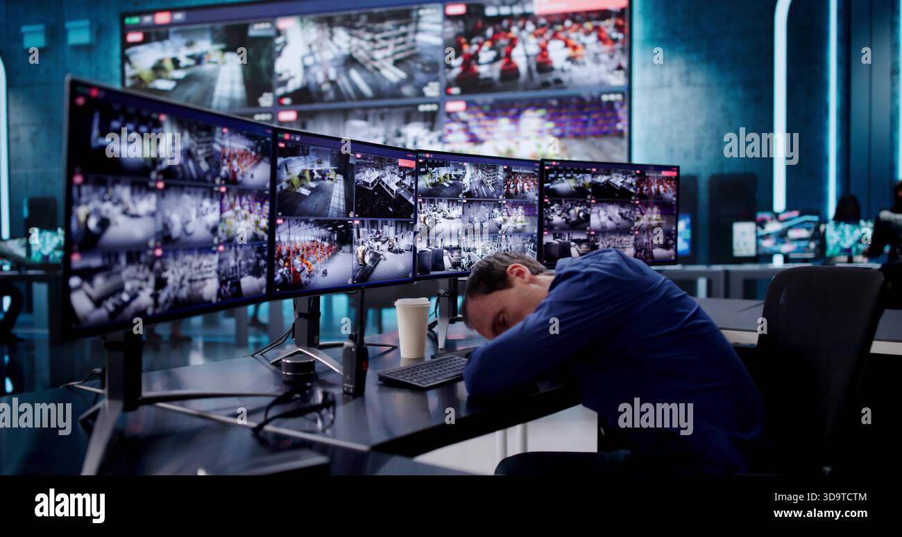 Guardia di sicurezza addormentata monitoraggio di più telecamere CCTV alla sua scrivania. Foto Stock