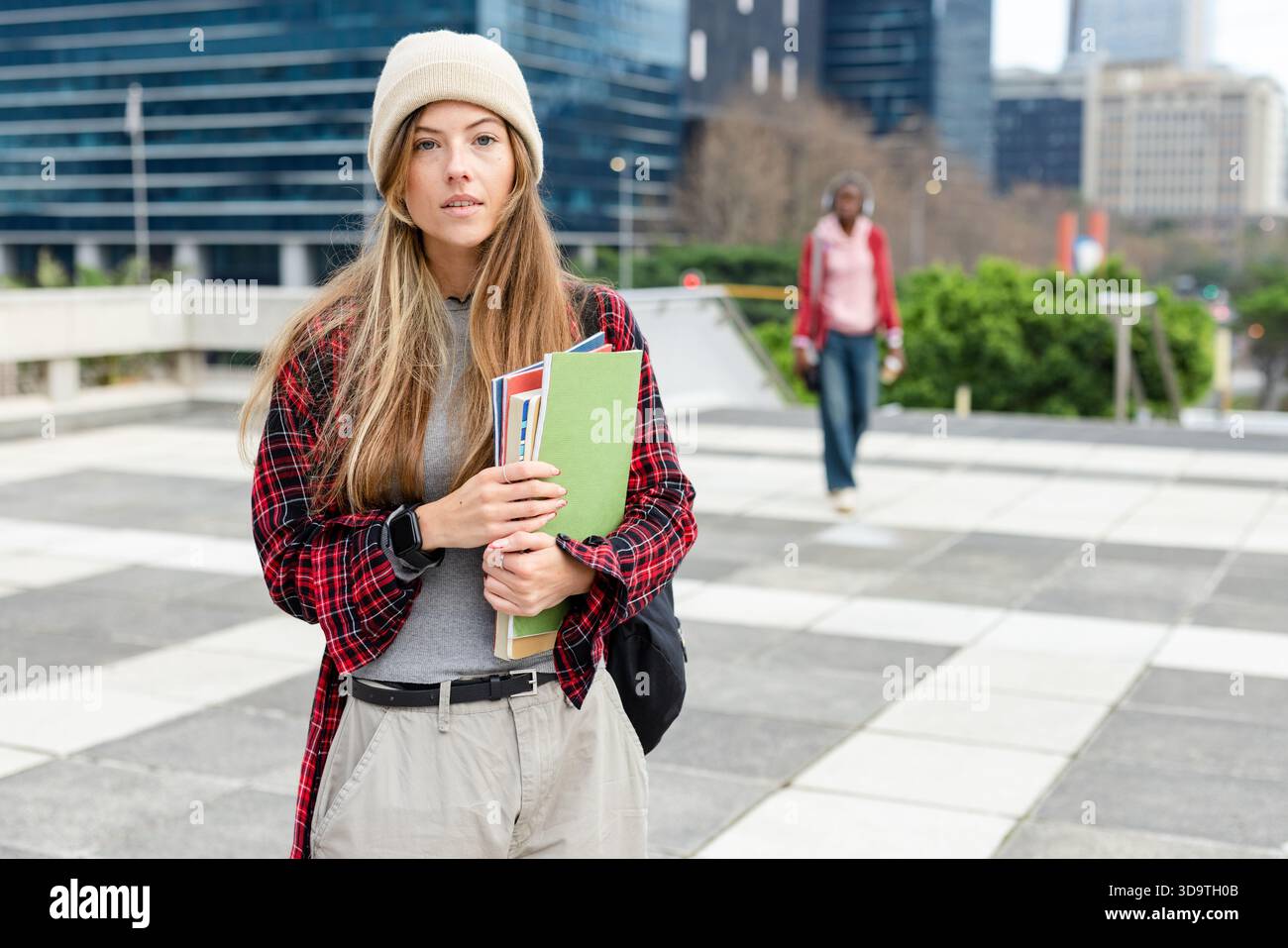 Adolescente in piedi in piazza con una cartella verde e un luminoso notebook con zaino Foto Stock