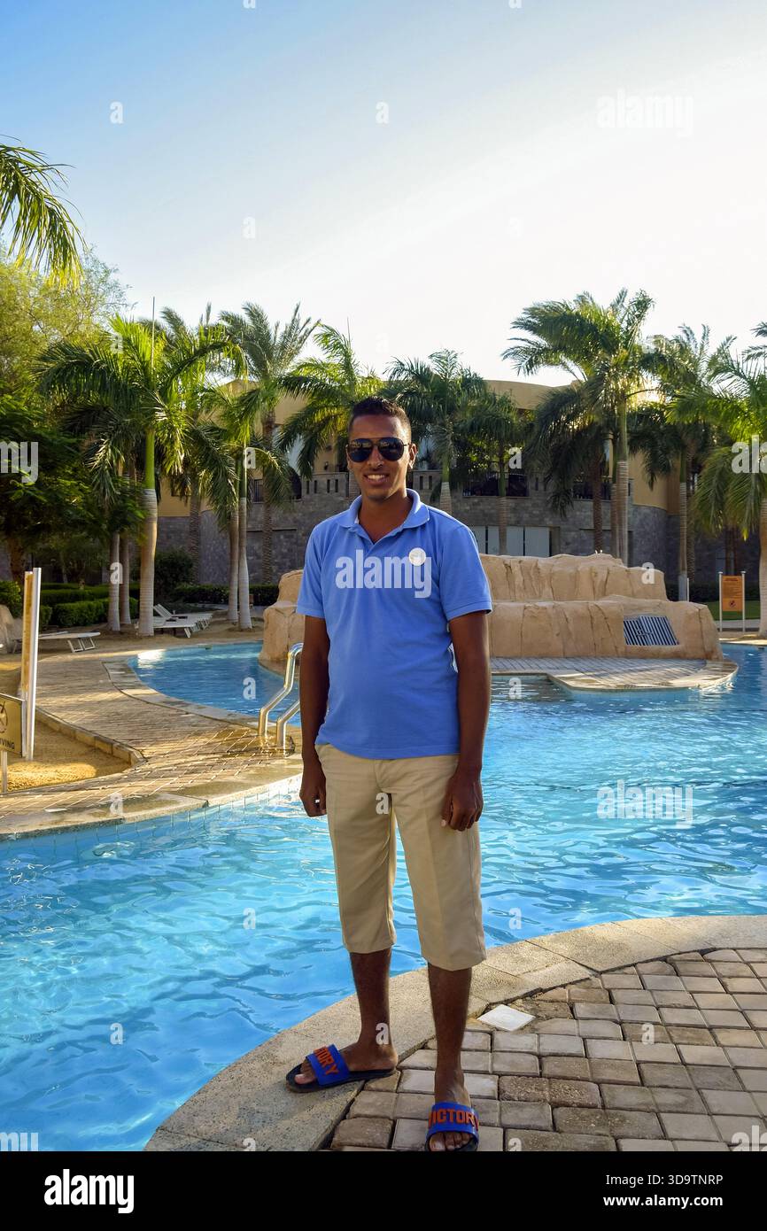 Hurghada, Egitto - 5 ottobre 2021: Un giovane uomo egiziano sorridente in occhiali da sole posa a bordo piscina presso l'hotel. Vacanze attive in Egitto, vacanze. Foto Stock