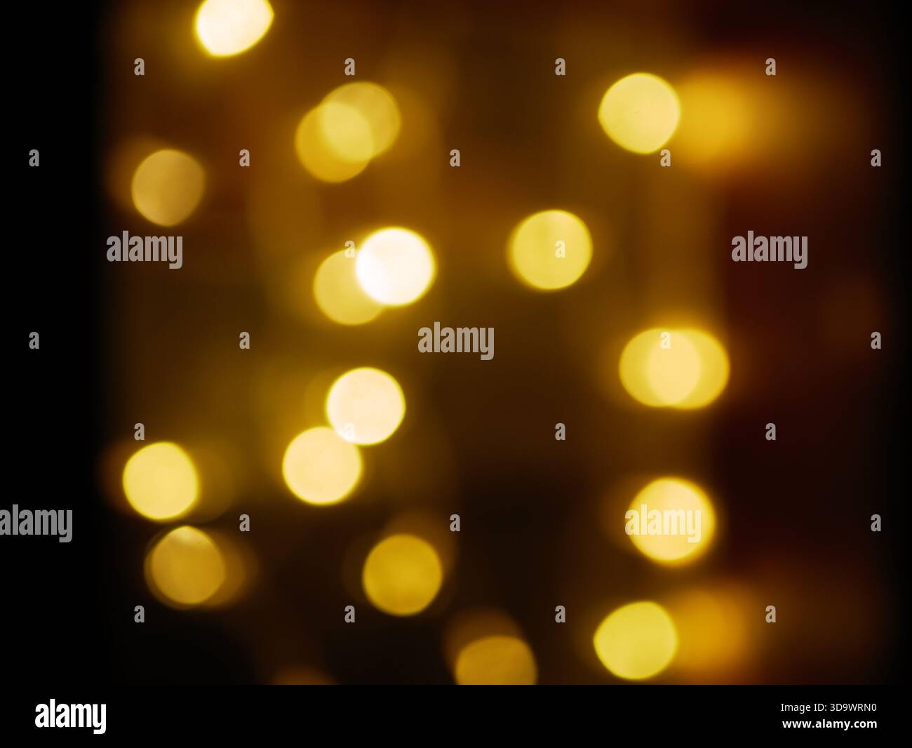 Calde luci bokeh dorate che si illuminano delicatamente su sfondo scuro, atmosfera astratta delle vacanze natalizie, texture di luci fiabe defocalizzate. Foto professionale. Alto Foto Stock