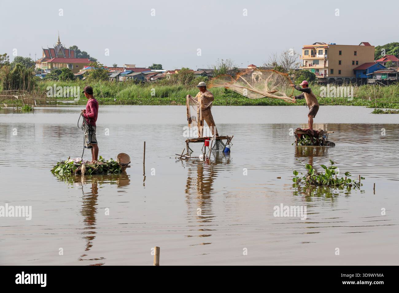 Fiume Tonle SAP, Cambogia. 7 dicembre 2025. I pescatori gettano le reti utilizzando metodi tradizionali da piattaforme galleggianti realizzate con materiali naturali. Raccolgono densi banchi di pesci d'acqua dolce durante l'inversione del flusso stagionale tra il lago e il Mekong. Con la fine della stagione dei monsoni e il deflusso ben avviato dall'inizio di ottobre, un gran numero di piccole specie fluviali viene convogliato attraverso il canale, generando un breve ma intenso periodo di pesca che rifornisce i mercati umidi, sostiene le diete domestiche e fornisce un reddito vitale per migliaia di famiglie lungo il fiume. Crediti: Kevin Izorce/Alamy Live News Foto Stock