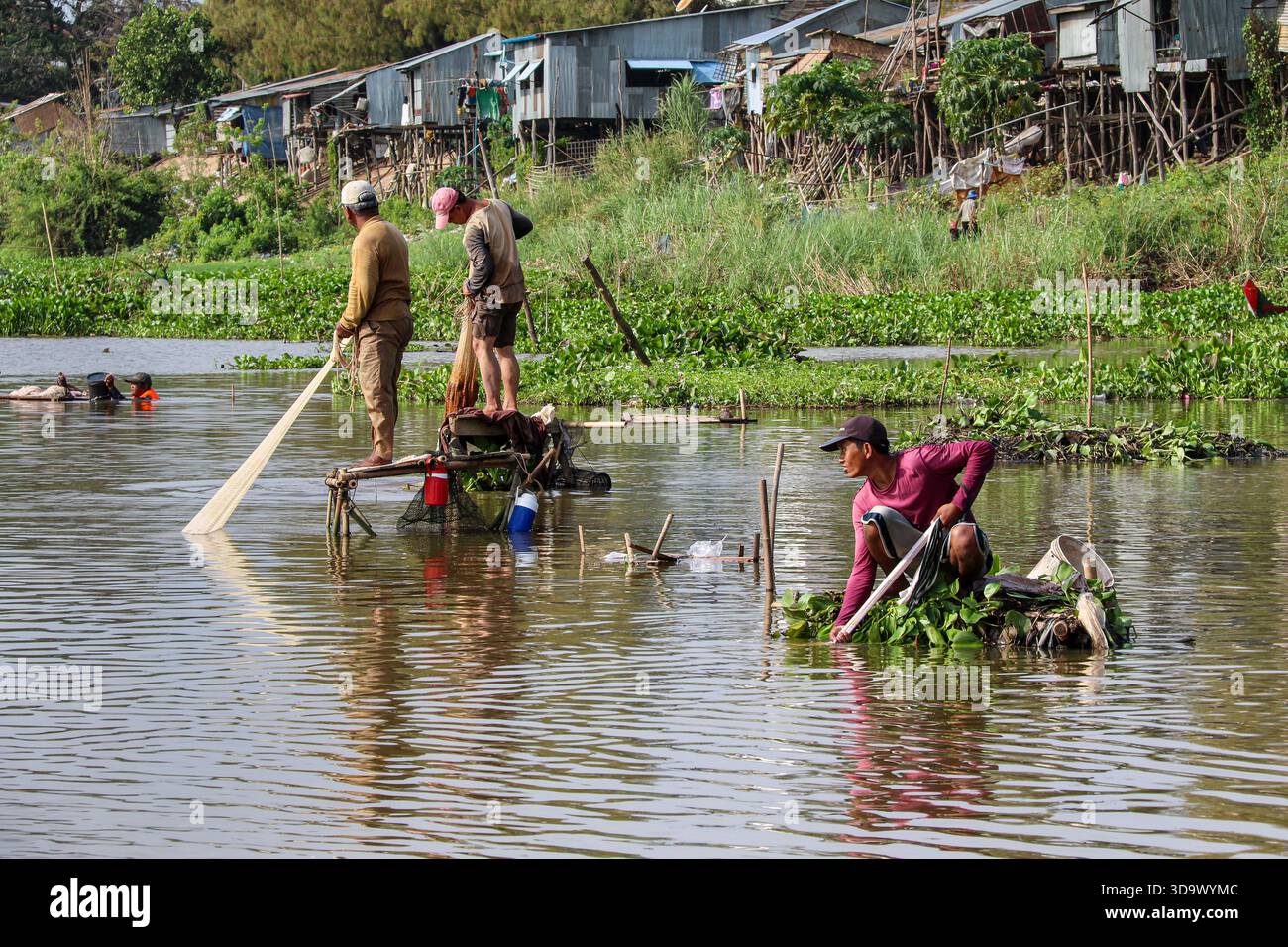 Fiume Tonle SAP, Cambogia. 7 dicembre 2025. I pescatori gettano le reti utilizzando metodi tradizionali da piattaforme galleggianti realizzate con materiali naturali. Raccolgono densi banchi di pesci d'acqua dolce durante l'inversione del flusso stagionale tra il lago e il Mekong. Con la fine della stagione dei monsoni e il deflusso ben avviato dall'inizio di ottobre, un gran numero di piccole specie fluviali viene convogliato attraverso il canale, generando un breve ma intenso periodo di pesca che rifornisce i mercati umidi, sostiene le diete domestiche e fornisce un reddito vitale per migliaia di famiglie lungo il fiume. Crediti: Kevin Izorce/Alamy Live News Foto Stock