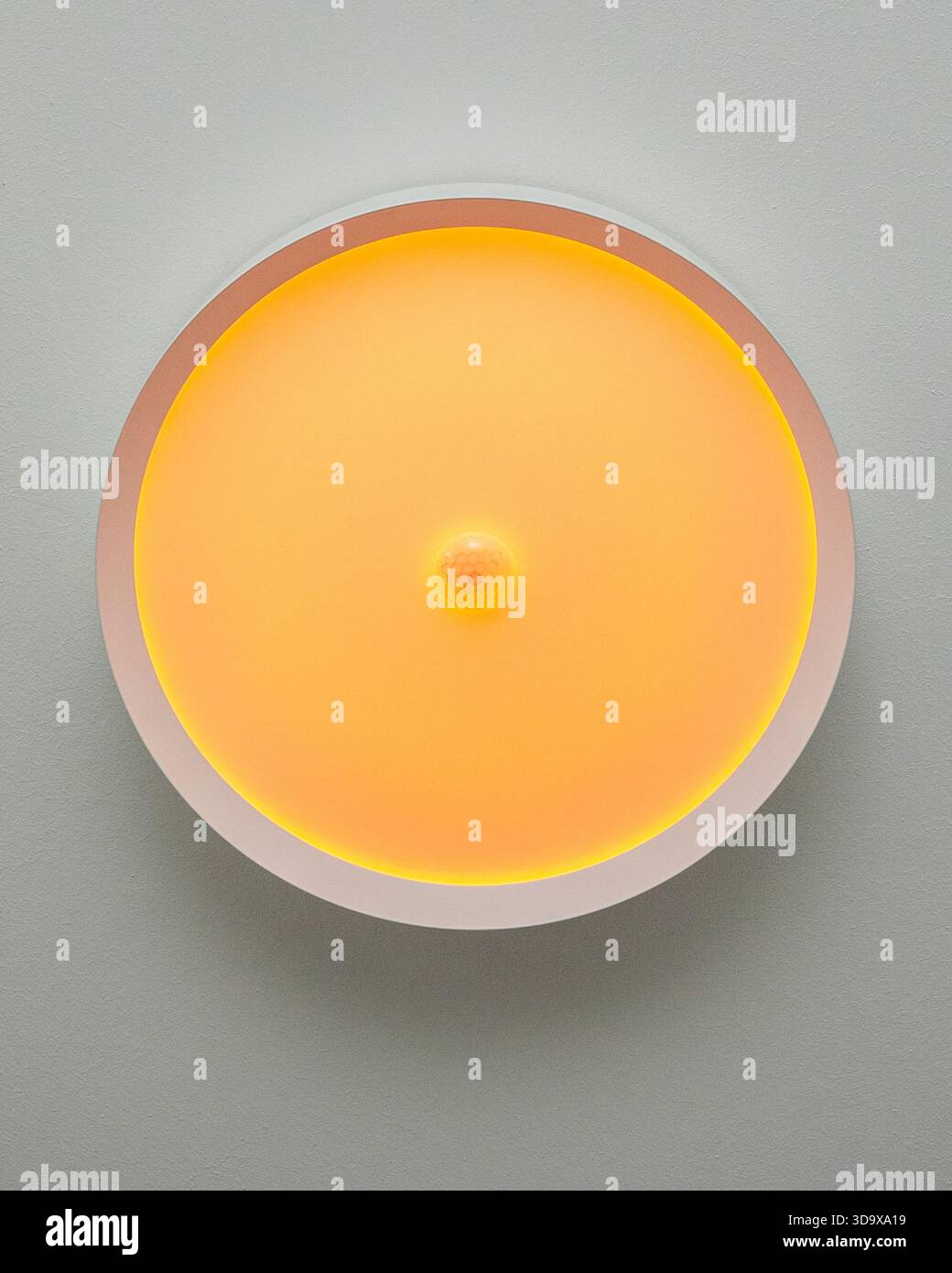 Lampada da parete rotonda che emette una luce gialla calda e soffusa. Design minimalista e pulito adatto a concetti di ambiente interno, atmosfera intima, casa Foto Stock