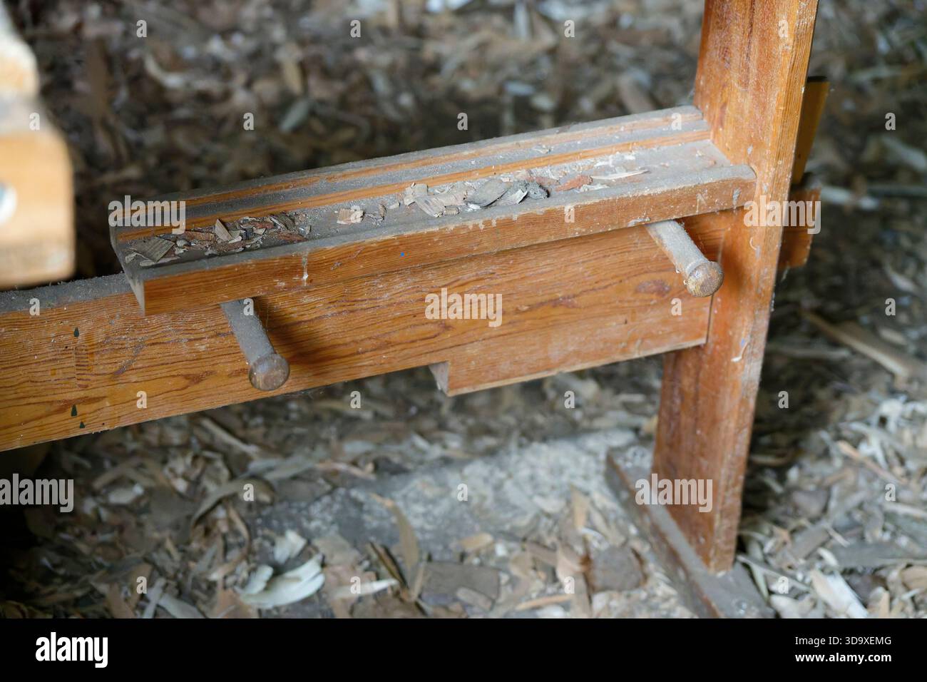 Una vista dettagliata di una panca in legno antico mostra superfici usurate e texture naturali circondate da foglie asciutte, evidenziando il carattere rustico all'aperto. Foto Stock