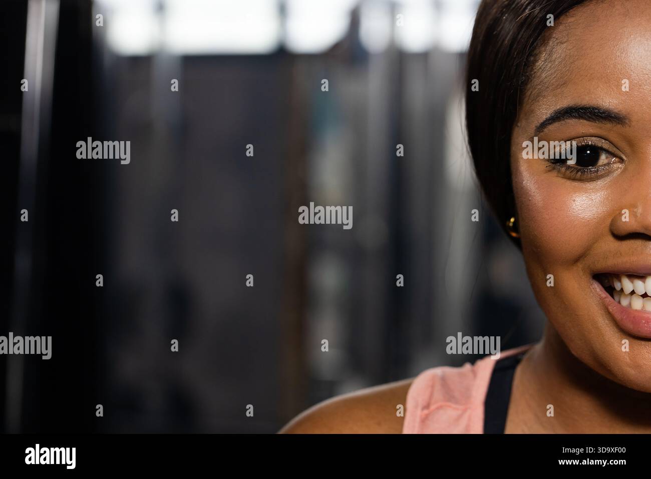 Il viso e la spalla della donna sorridente si esibiscono in palestra con attrezzature sfocate e spazio per copiare Foto Stock