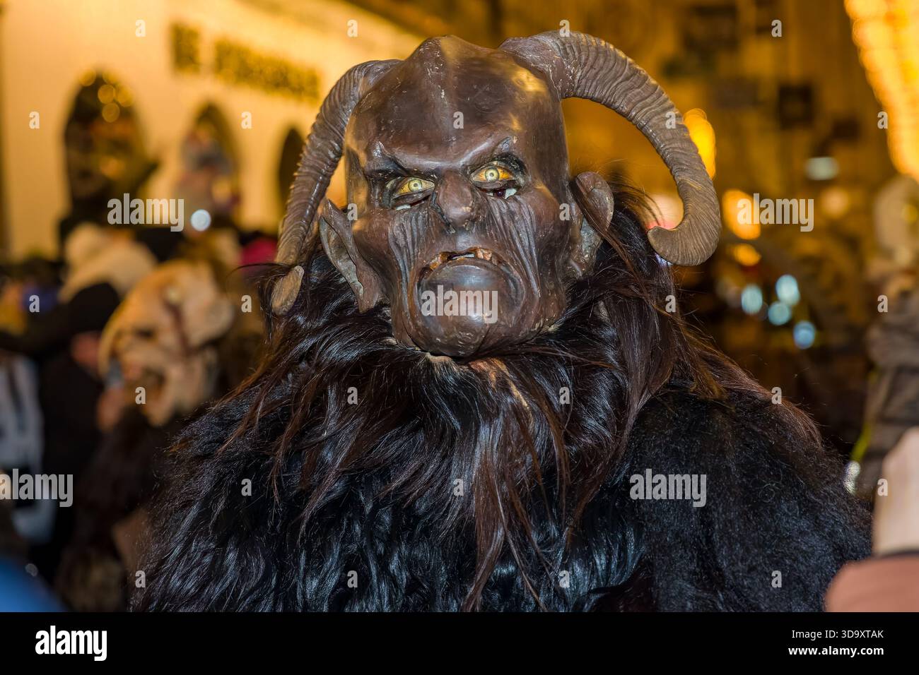 Artista che indossa un costume demoniaco Krampus con occhi brillanti in un festival invernale Foto Stock