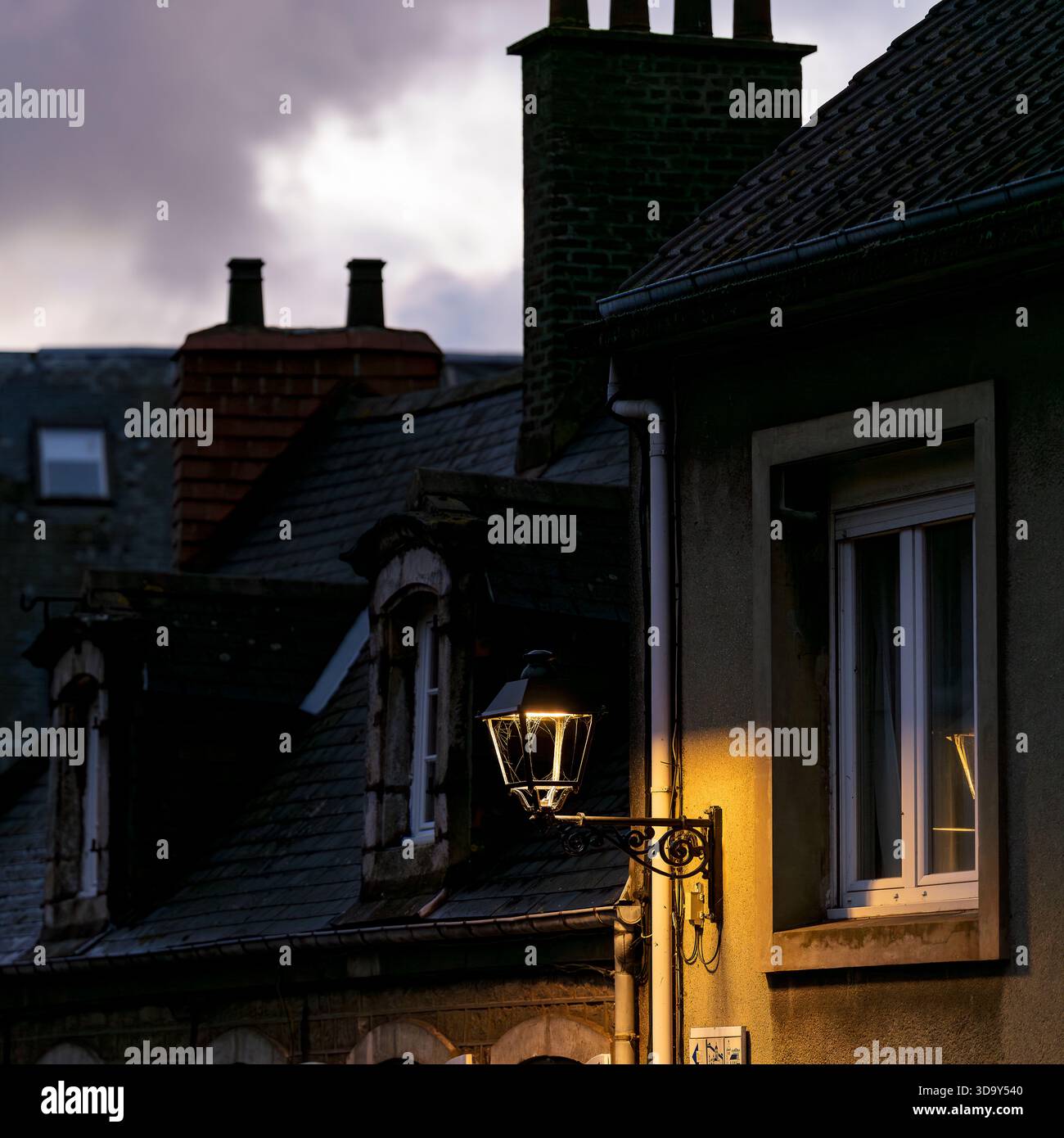 Calda lanterna che illumina i tetti storici al crepuscolo nella città vecchia di Boulogne-sur-Mer. Bagliore di sera sulla tradizionale architettura francese. Foto Stock
