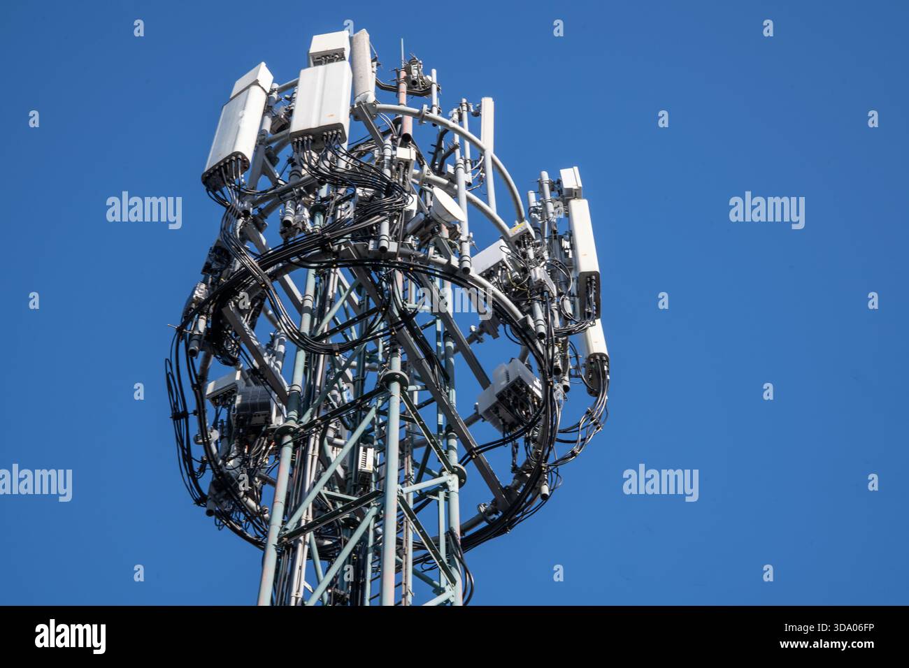 Un'asta di telefonia mobile alta catturata contro un cielo azzurro, che mostra la moderna infrastruttura di rete cellulare e le apparecchiature di telecomunicazione Foto Stock