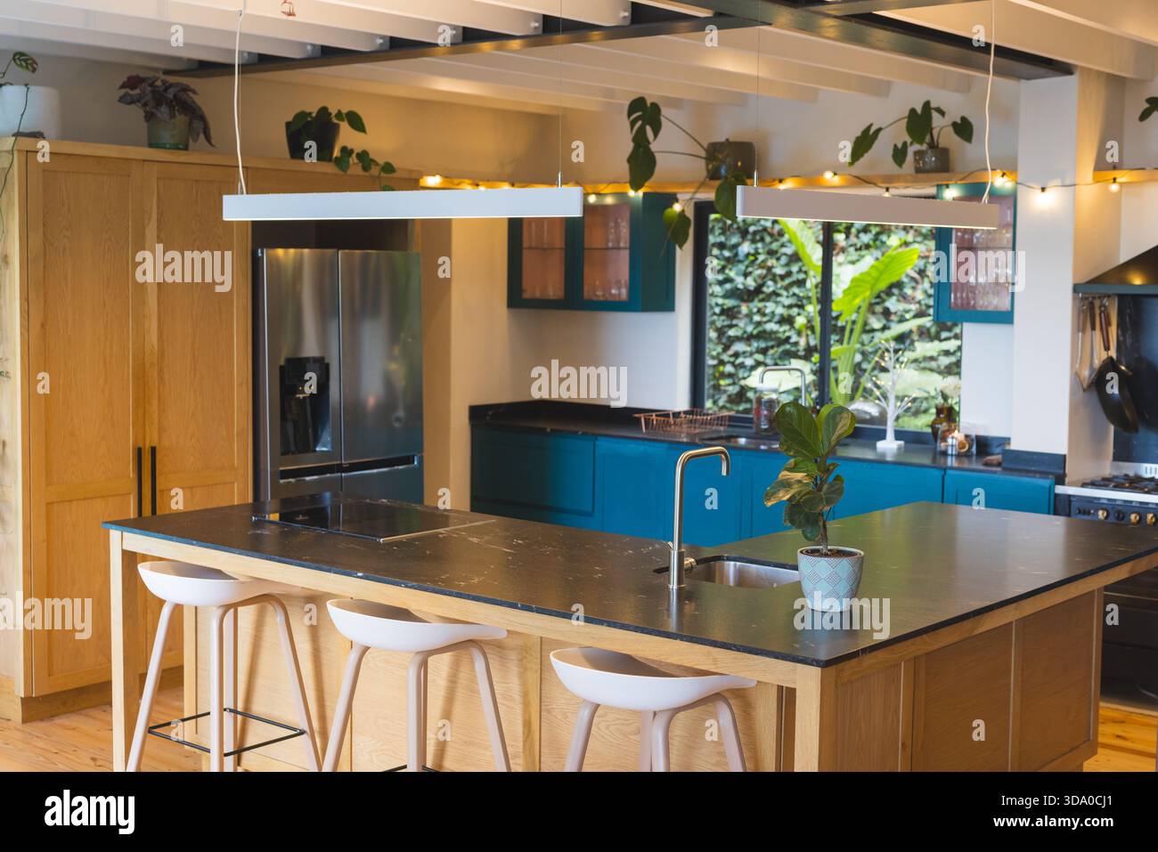 La cucina in legno che occupa il centro abitato è incentrato sulla cucina con luci a sospensione e sgabelli da bar Foto Stock