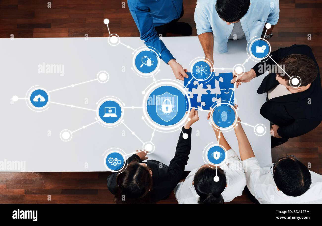 Un team diversificato collabora a una strategia di sicurezza informatica, utilizzando pezzi di puzzle per simboleggiare la connessione e la protezione in uno spazio di lavoro digitale, favorendo Foto Stock