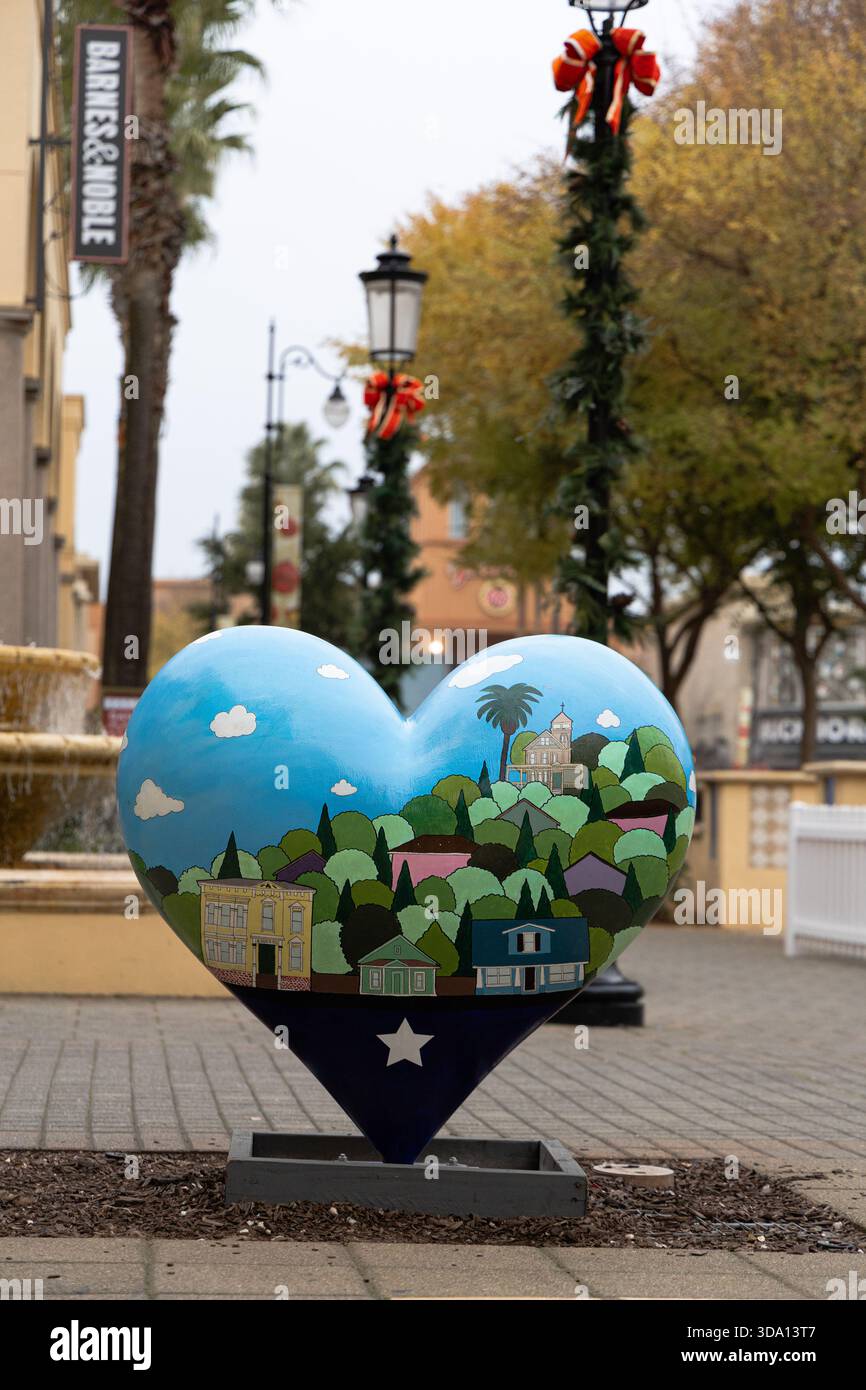 Una scultura a forma di cuore mostra le raffigurazioni di edifici locali e della natura in un parco cittadino. Le decorazioni natalizie sono visibili intorno all'area. Foto Stock