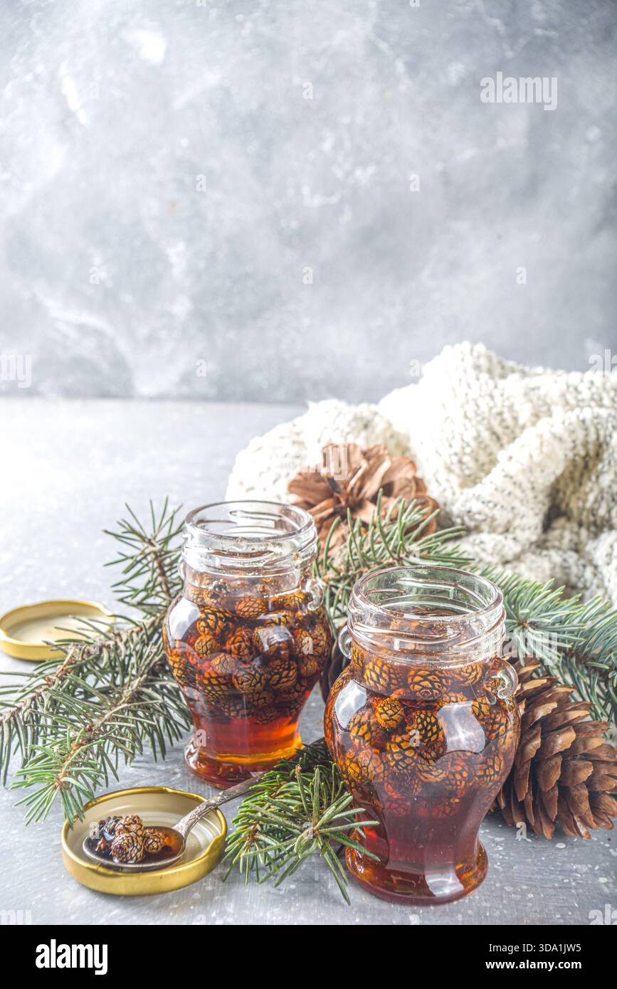 Tradizionale marmellata di dolci siberiani e ucraini. Confettura di coni di pino fatta in casa in piccoli vasi carini, con coni di pino e rami Foto Stock