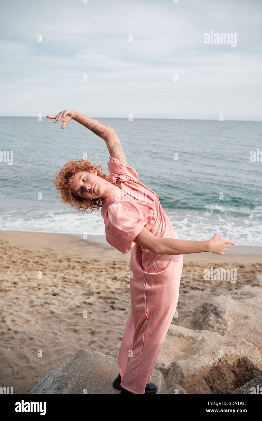 Donna che balla liberamente sulla spiaggia indossando la tuta Foto Stock