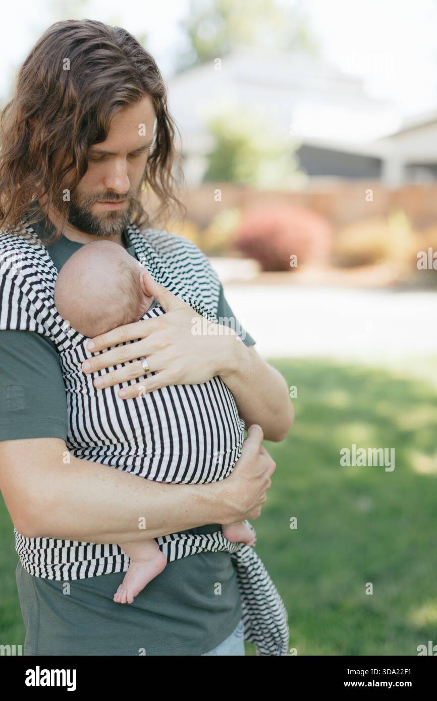 Rimani a casa, papà indossa il neonato all'aperto e si prende cura di te Foto Stock