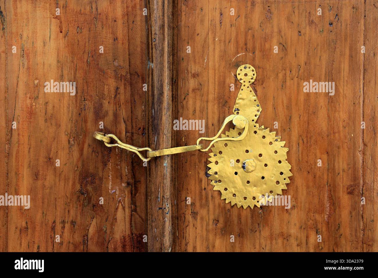 Maniglia in metallo su vecchia porta in legno marrone. La maniglia della portiera è verniciata in oro. Foto Stock