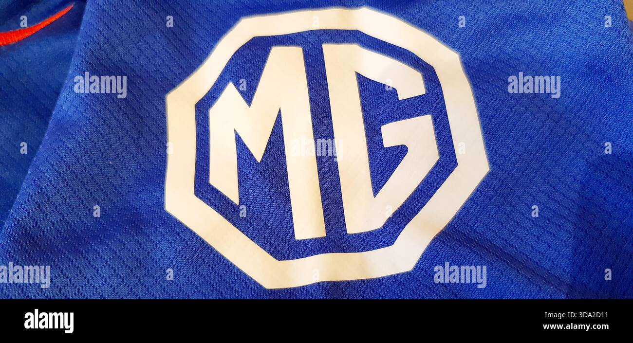 Il logo della casa automobilistica britannica MG (Morris Garages) su una maglietta, di proprietà del gigante automobilistico cinese SAIC Motor Corporation Foto Stock