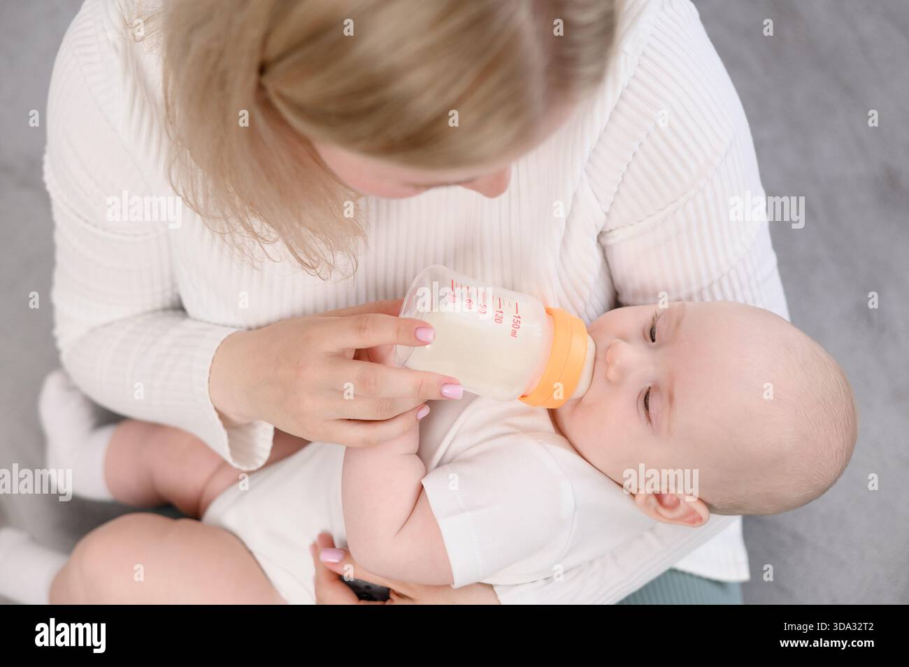 La tata tiene con cura l'infarto tra le braccia, il bambino beve la formula dal biberon tenuto dalla donna, primo piano. Concetto di alimentazione sana, nutrizione artificiale, io Foto Stock