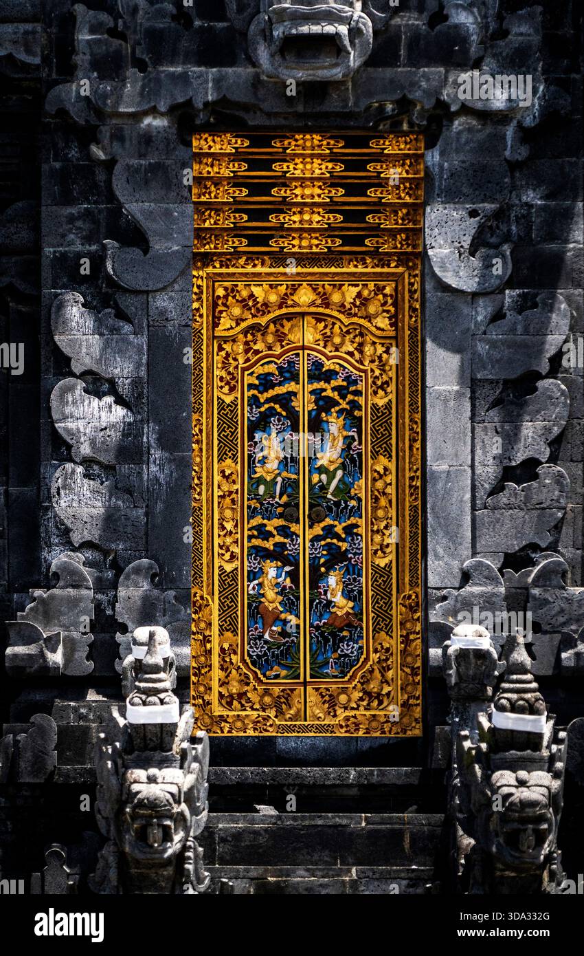 Porta dorata ornata con intricate incisioni in un tempio di pietra scura. Foto Stock