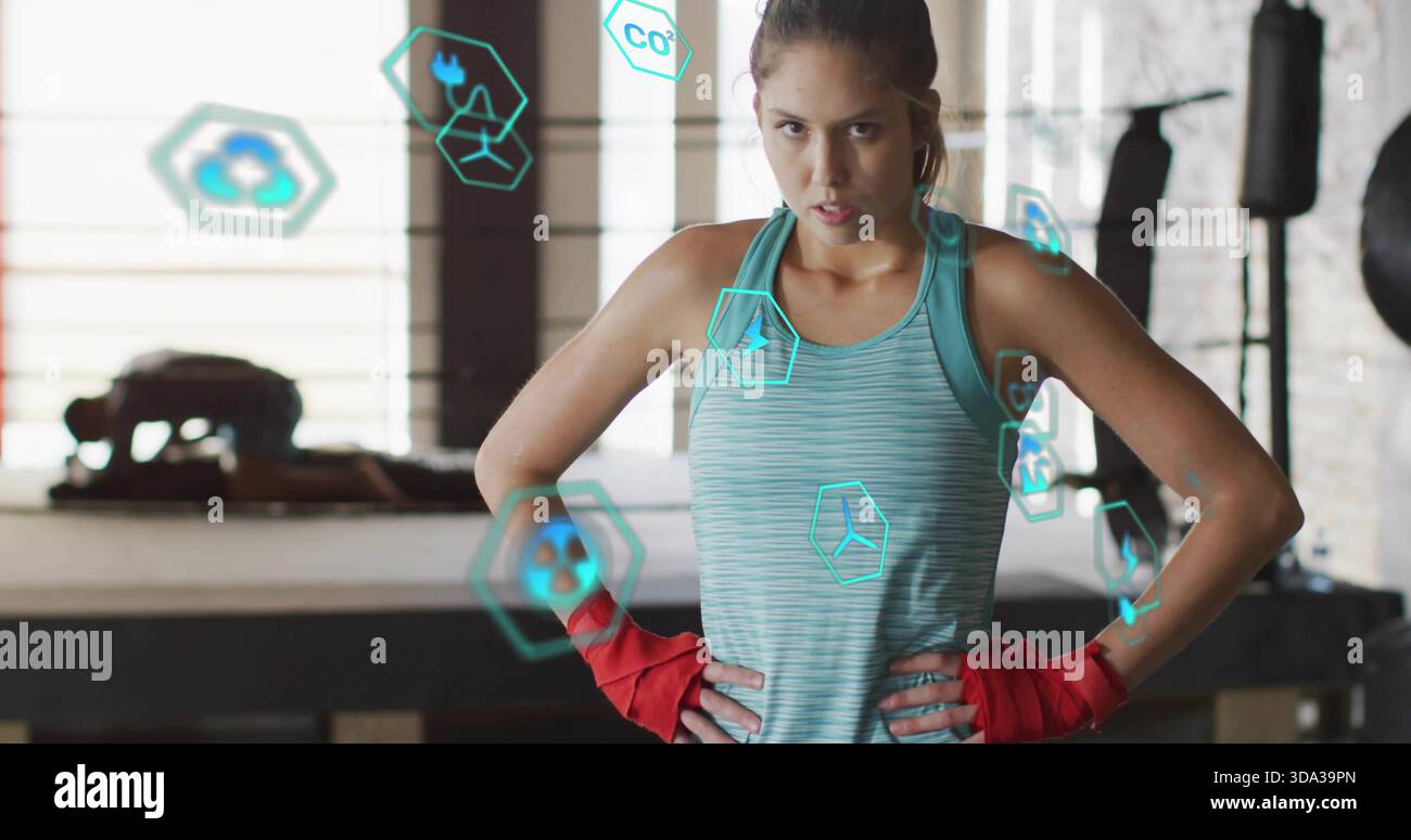Atleta in piedi che posa le mani sui fianchi nell'anello di pugilato, indossa canotta color acqua e avvolgimenti rossi Foto Stock