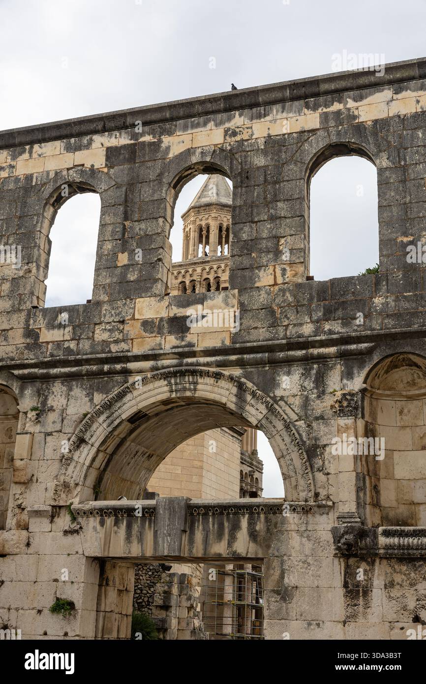 Le antiche rovine in pietra fanno da cornice a un lontano campanile, offrendo uno scorcio di architettura storica e del patrimonio senza tempo attraverso archi e robusti Foto Stock