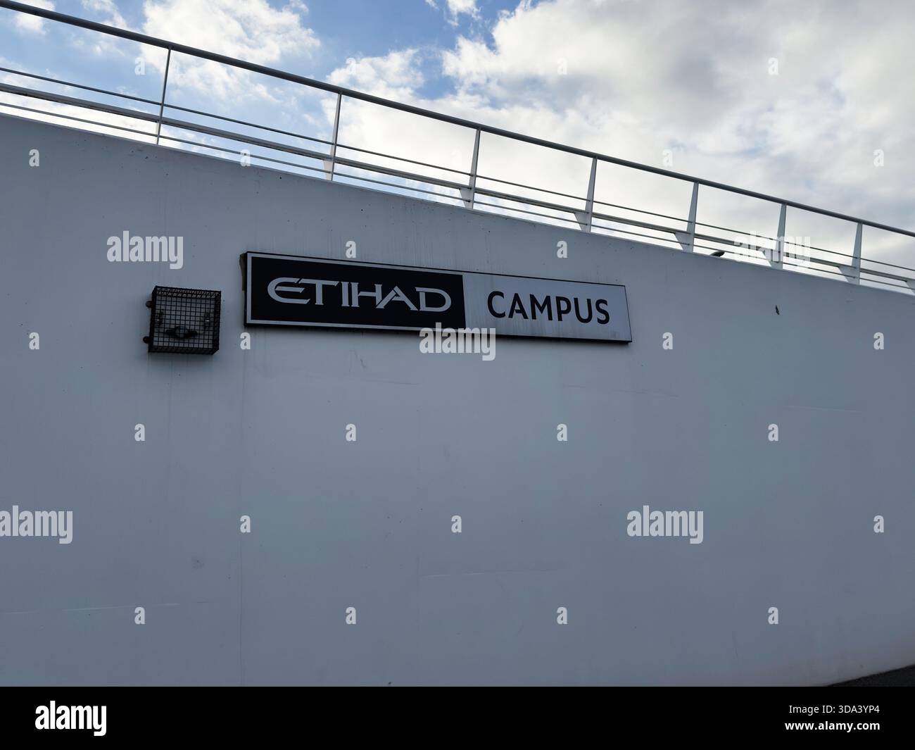 Manchester, Regno Unito - 16 novembre 2025: Cartello Etihad Campus sul muro bianco fuori dallo stadio di Manchester, cielo blu e ringhiera sopra. Foto Stock