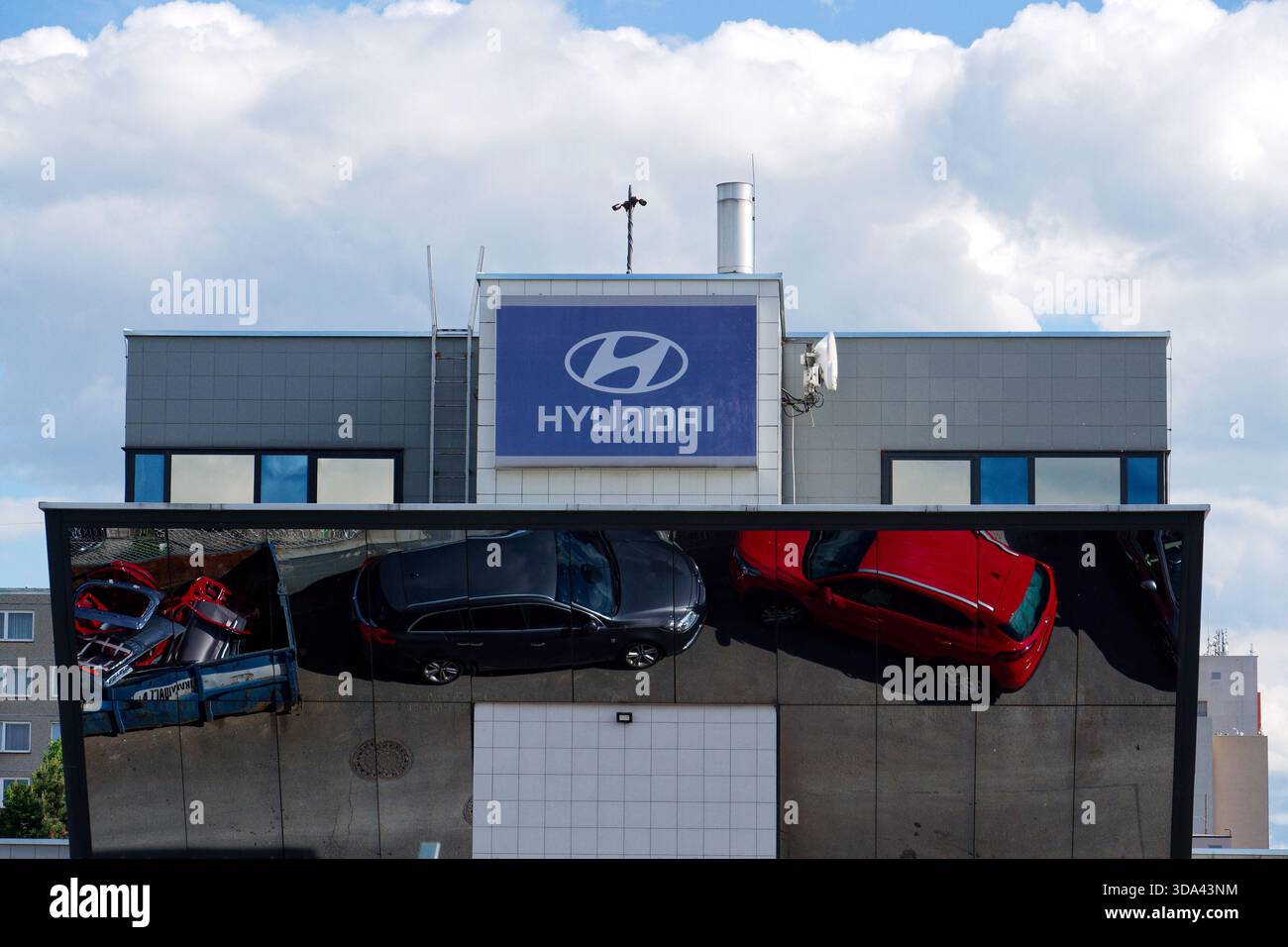 Logo dell'azienda Hyundai sull'edificio della concessionaria con auto e parti di ricambio che si riflettono in un contenitore di ferro il 29 maggio 2025 a Praga, repubblica Ceca. Foto Stock