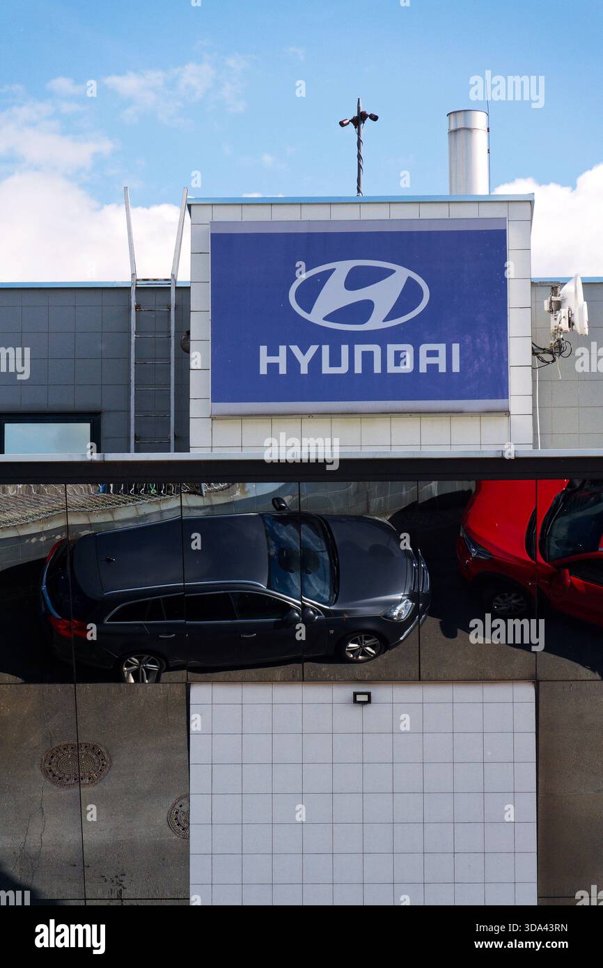 Logo dell'azienda Hyundai sull'edificio della concessionaria con auto e parti di ricambio che si riflettono in un contenitore di ferro il 29 maggio 2025 a Praga, repubblica Ceca. Foto Stock