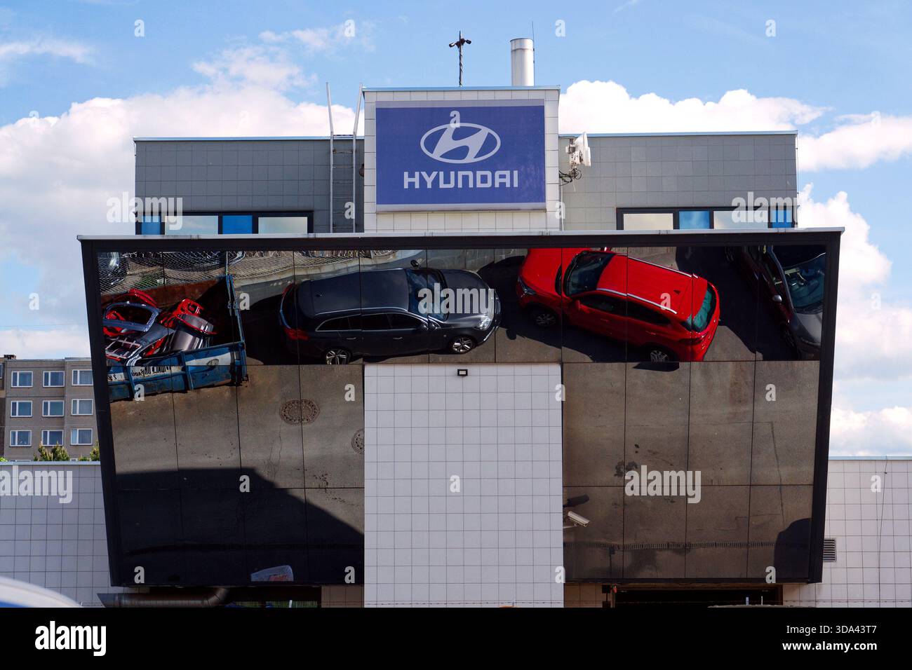 Logo dell'azienda Hyundai sull'edificio della concessionaria con auto e parti di ricambio che si riflettono in un contenitore di ferro il 29 maggio 2025 a Praga, repubblica Ceca. Foto Stock