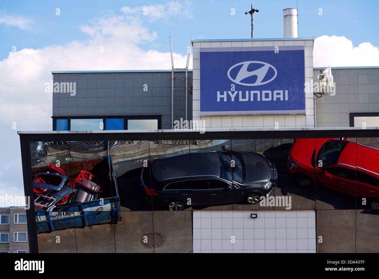 Logo dell'azienda Hyundai sull'edificio della concessionaria con auto e parti di ricambio che si riflettono in un contenitore di ferro il 29 maggio 2025 a Praga, repubblica Ceca. Foto Stock