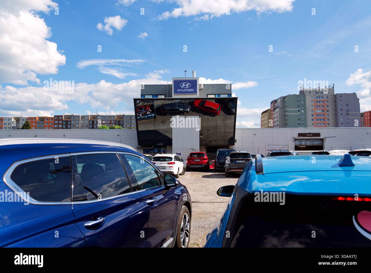 Logo dell'azienda Hyundai sull'edificio della concessionaria con auto e parti di ricambio che si riflettono in un contenitore di ferro il 29 maggio 2025 a Praga, repubblica Ceca. Foto Stock