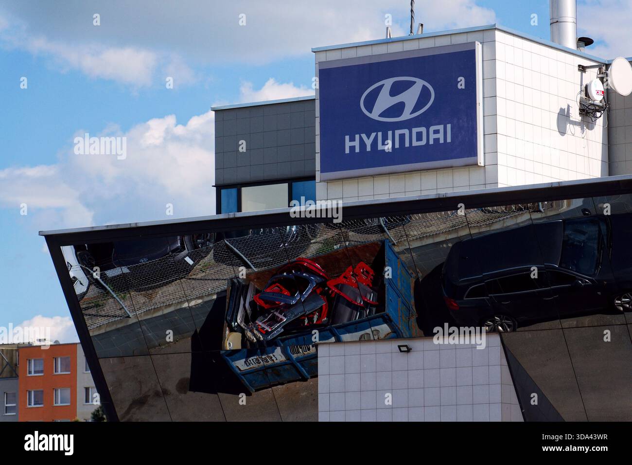 Logo dell'azienda Hyundai sull'edificio della concessionaria con auto e parti di ricambio che si riflettono in un contenitore di ferro il 29 maggio 2025 a Praga, repubblica Ceca. Foto Stock