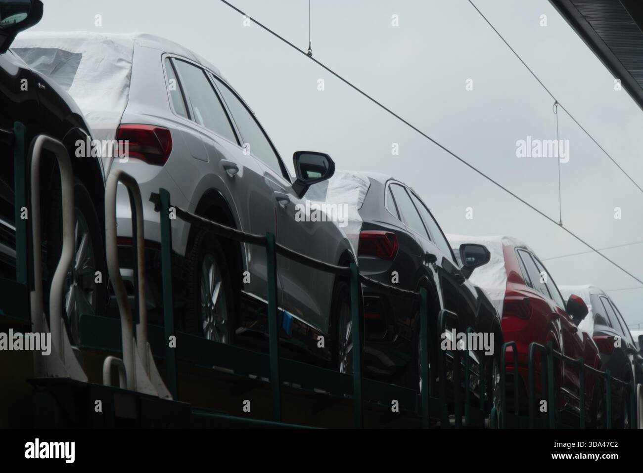 Auto nuove con coperture protettive bianche sul trasportatore ferroviario Foto Stock
