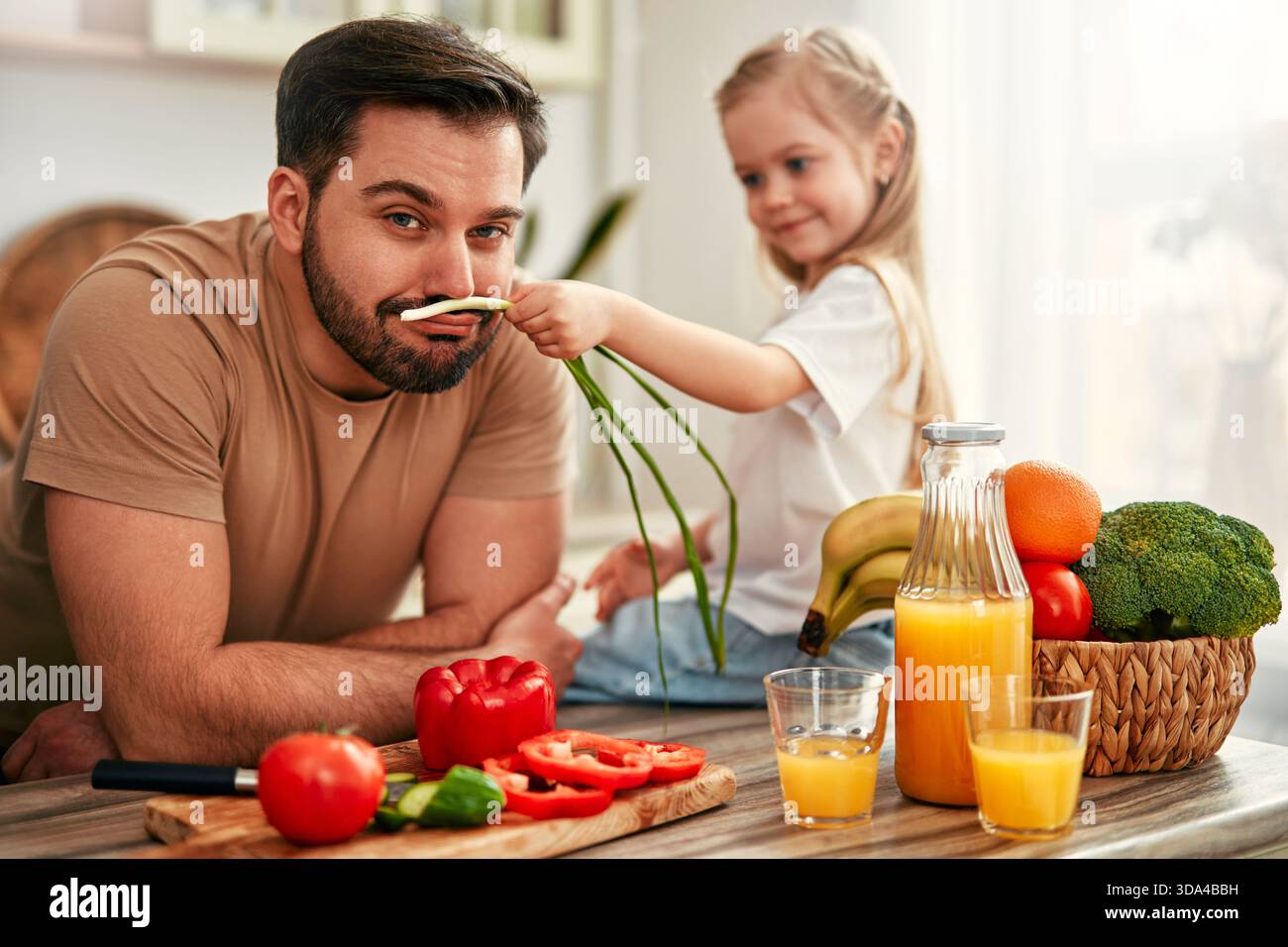 In un ambiente accogliente, un allegro legame padre e figlia con una sana colazione a base di verdure fresche, frutta e succo d'arancia, condividendo affetti Foto Stock